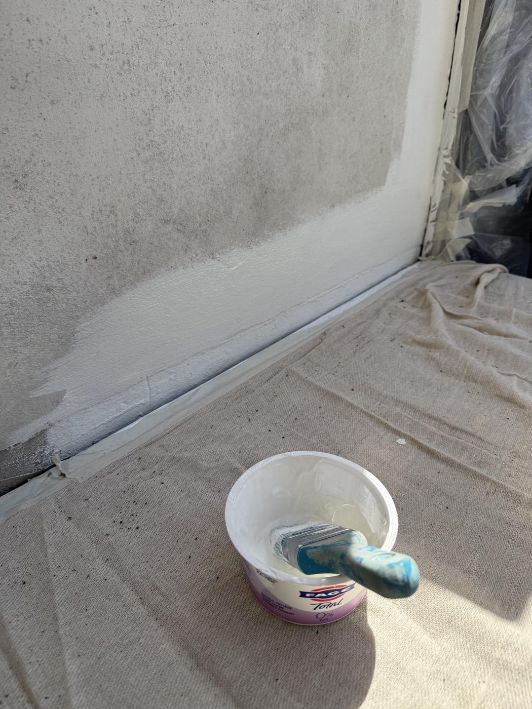 The first coat of masonry paint going on