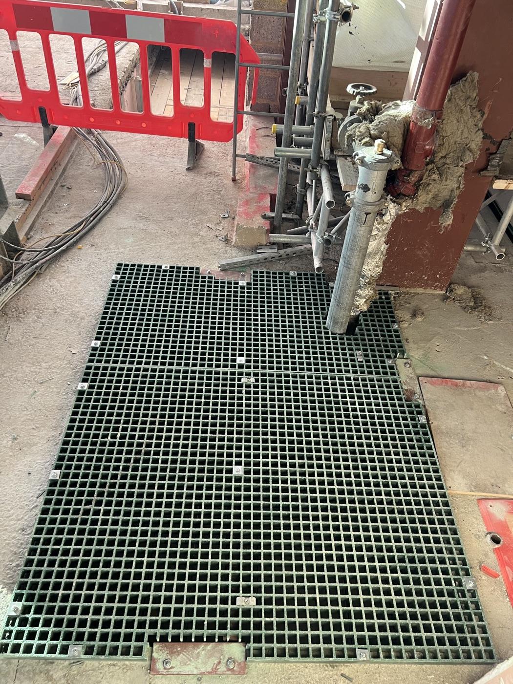 After: grating cut neatly around pipework and fixed down