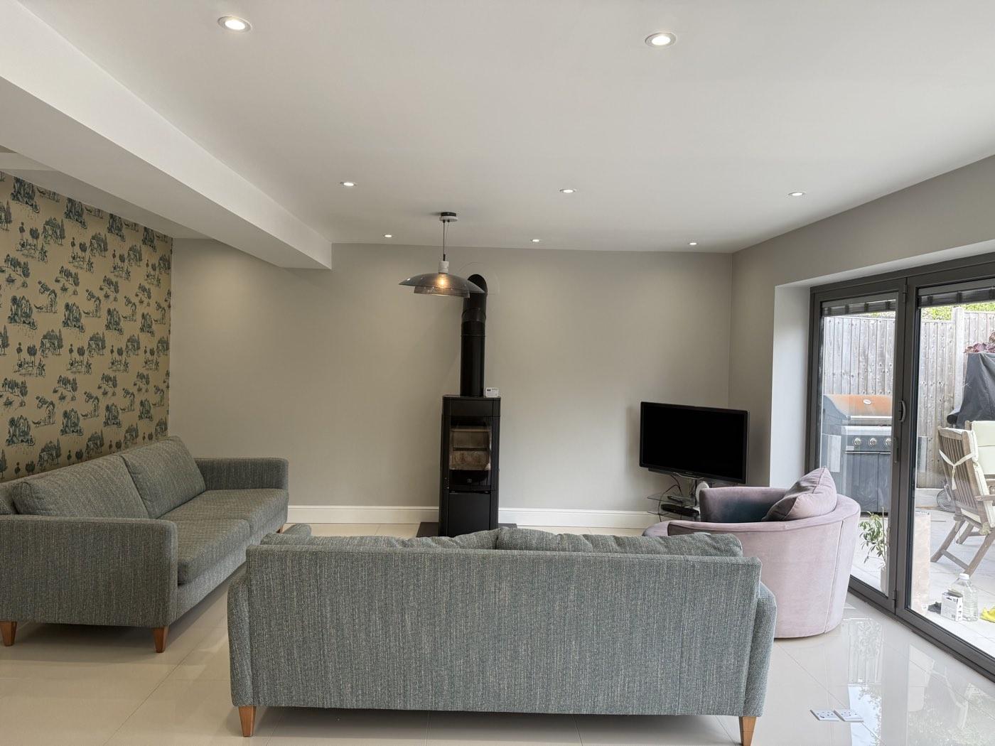 After: the lounge area with feature wallpaper and wood burner